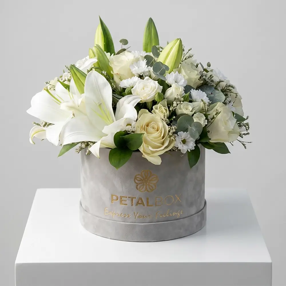 Elegant white lily and rose flower box arrangement with white chrysanthemums, eucalyptus, and fresh greenery in a luxury Petal Box floral display.