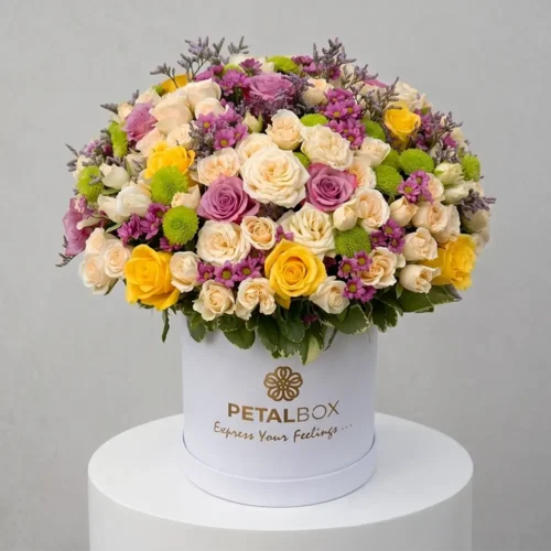 luxury mixed flower box with yellow roses, lavender roses, white spray roses and purple chrysanthemums in an elegant white hat box, premium floral arrangement by Petal Box UAE for flower delivery in Abu Dhabi and Dubai