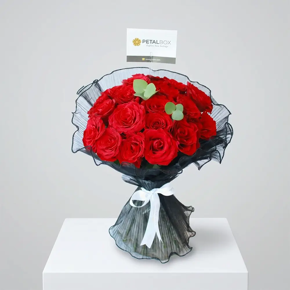 Luxury red rose bouquet with elegant black mesh wrapping, white ribbon, and fresh red roses styled for premium romantic gifting by Petal Box.