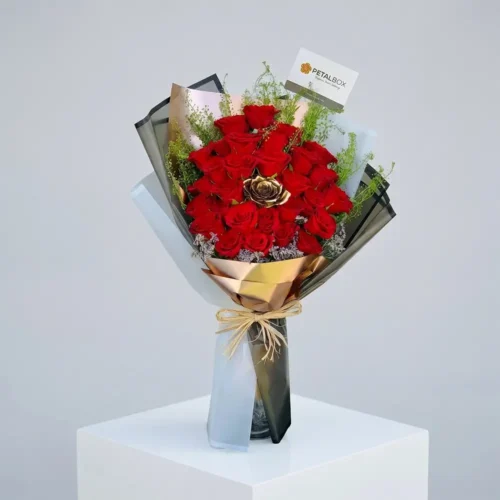 Luxury red rose bouquet with premium black and gold wrapping, featuring a golden rose centerpiece and fresh greenery for elegant romantic gifting by Petal Box UAE.