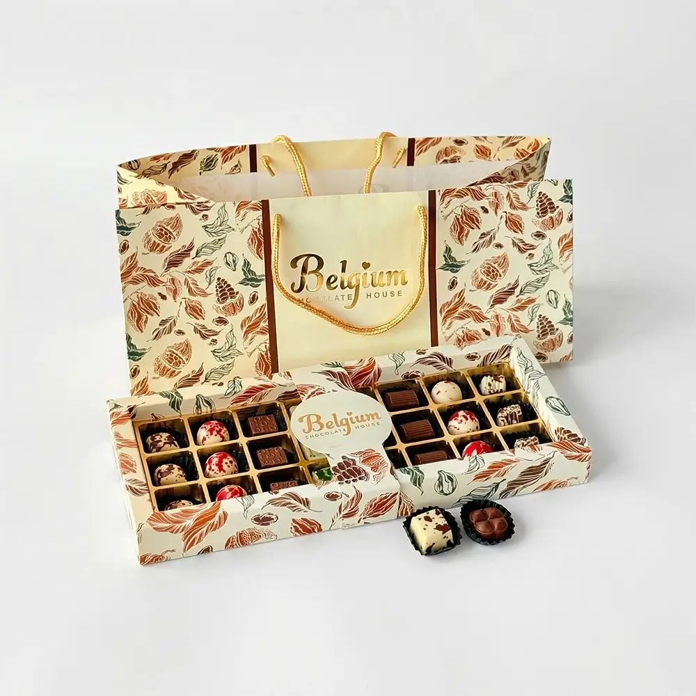 Belgium Chocolate House premium assorted chocolate gift box with 24 handcrafted chocolates including truffles, nut pralines, and milk chocolate pieces, presented in a decorative botanical-print gift box and matching luxury shopping bag